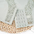 Close-up of light gray hook-and-eye closure with lace trim detail, displayed on woven placemat