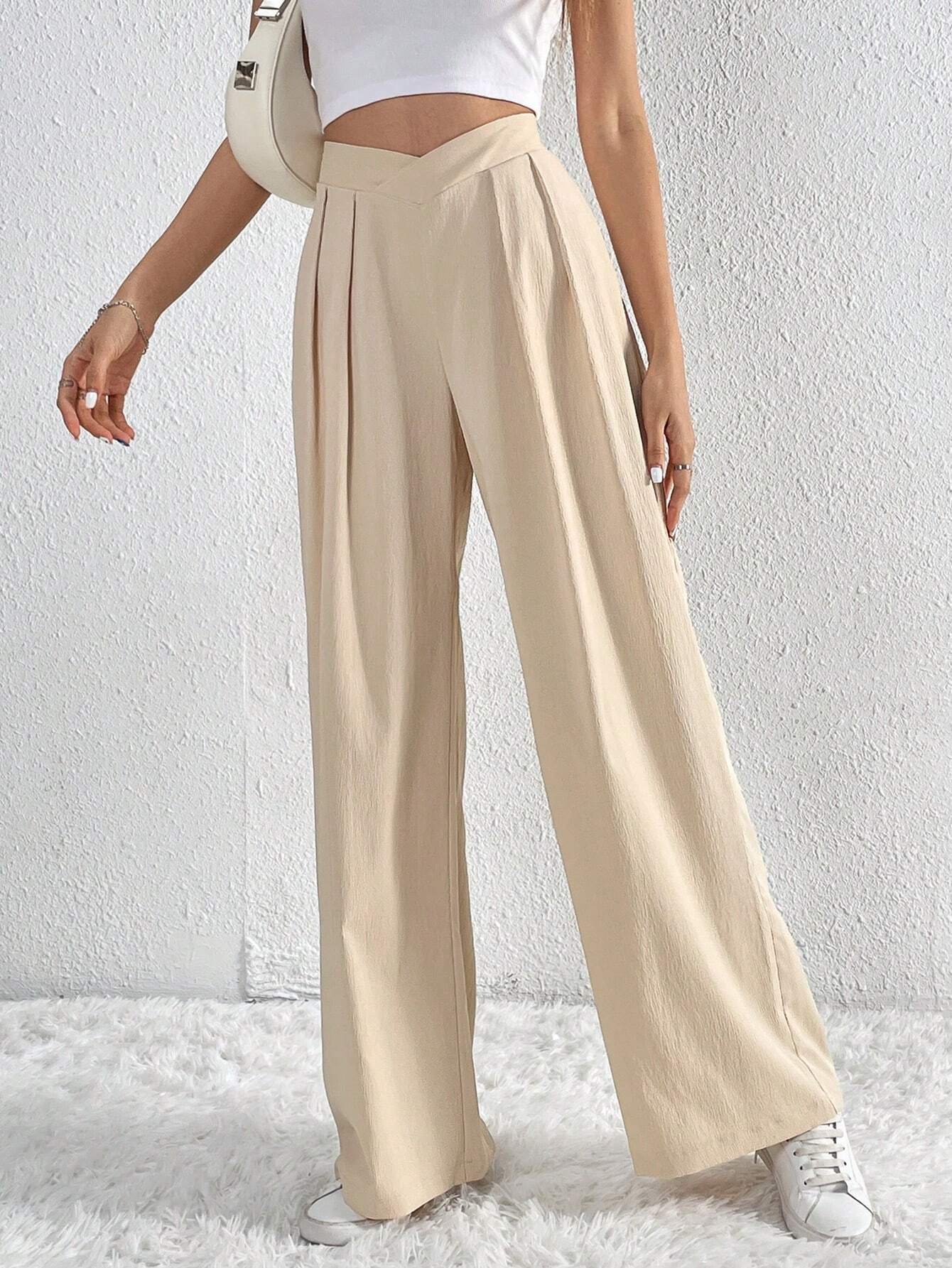 Front view of beige pleated wide-leg trousers styled with white crop top.