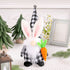Easter gnome plush with bunny ears, black-and-white plaid hat, long white beard, and a plush carrot in hand, placed on a table.