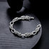A silver rope-style chain bracelet placed on a black circular plate, showing its intricate knot design and polished finish.