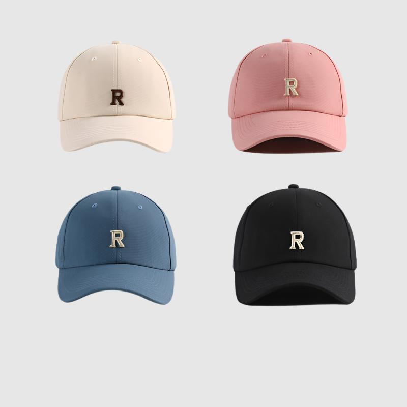Four baseball caps with 'R' logo in beige, pink, blue, and black, displayed in grid layout with metallic embroidery