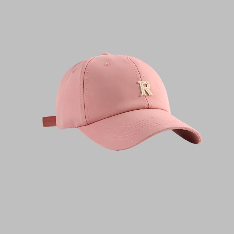 Pink baseball cap with gold 'R' logo embroidery, featuring curved brim and adjustable back strap