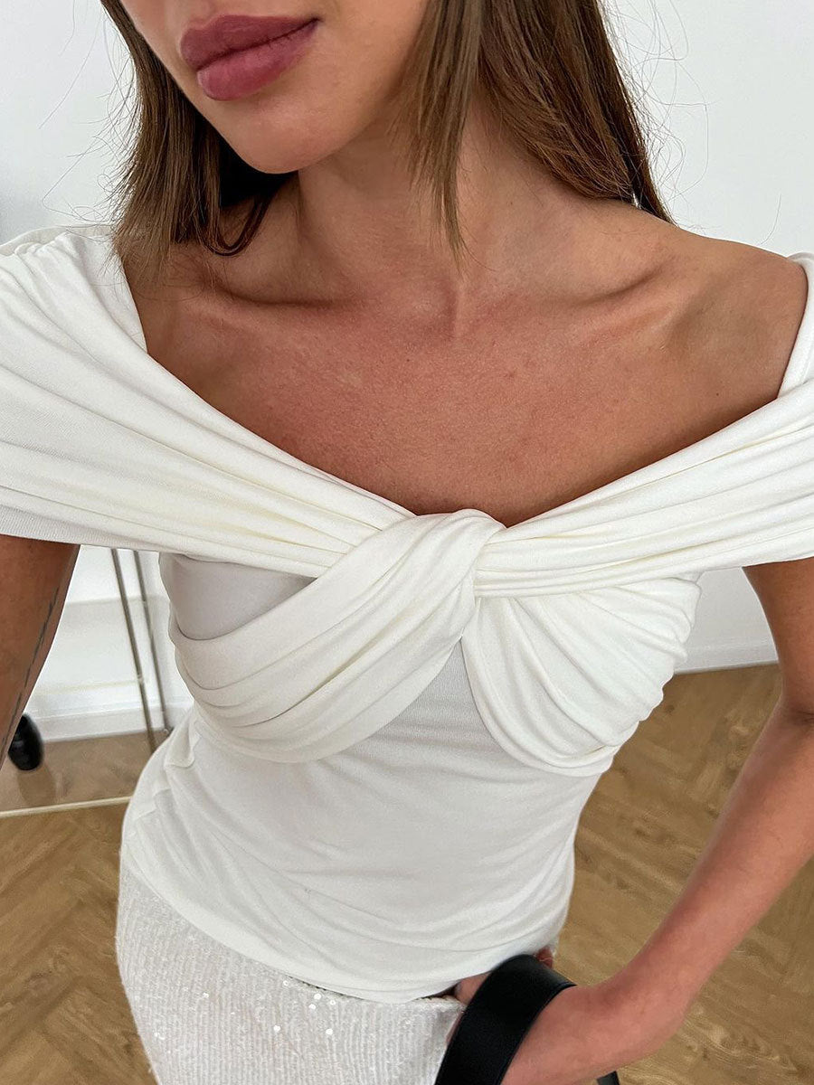 Extreme close-up of the twisted knot detail on a white off-shoulder top, highlighting the fabric draping
