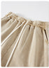 A close-up of beige drawstring shorts featuring an elastic waistband and white drawstrings, made of soft washed fabric