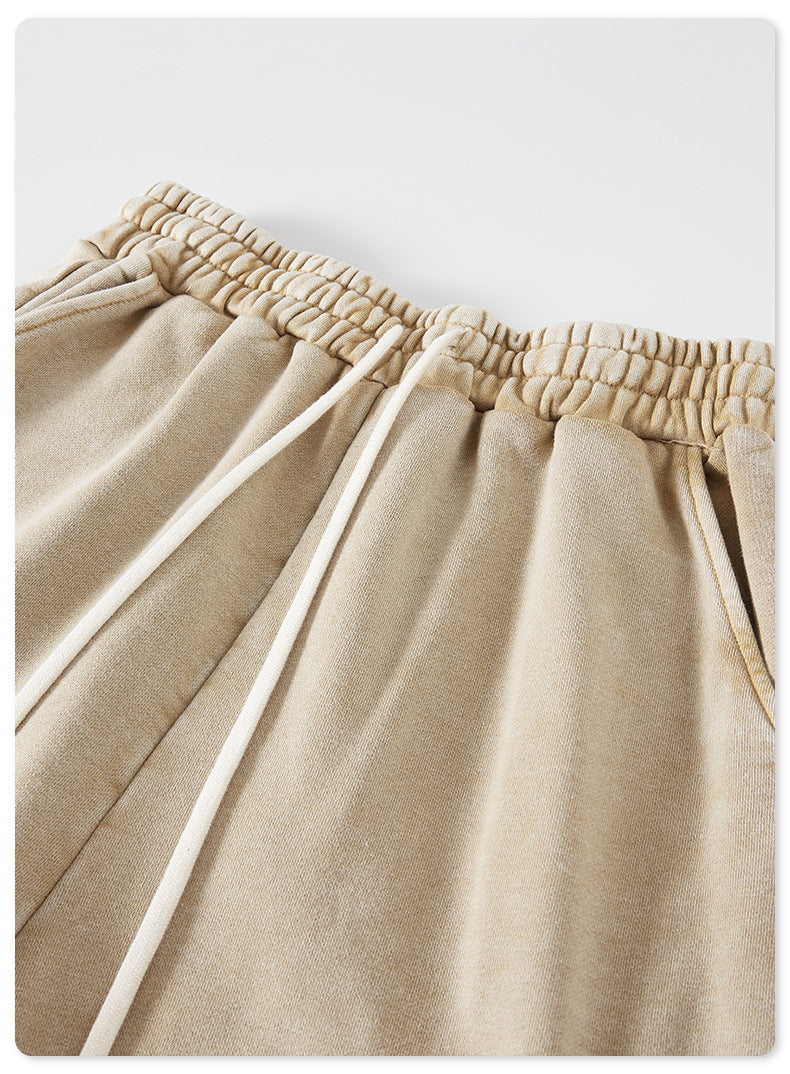 A close-up of beige drawstring shorts featuring an elastic waistband and white drawstrings, made of soft washed fabric