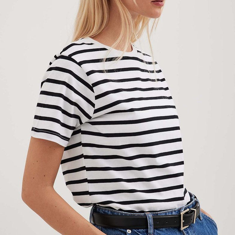 Blonde woman in black and white striped tee, paired with blue denim and black belt