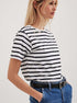 Blonde woman in black and white striped tee, paired with blue denim and black belt