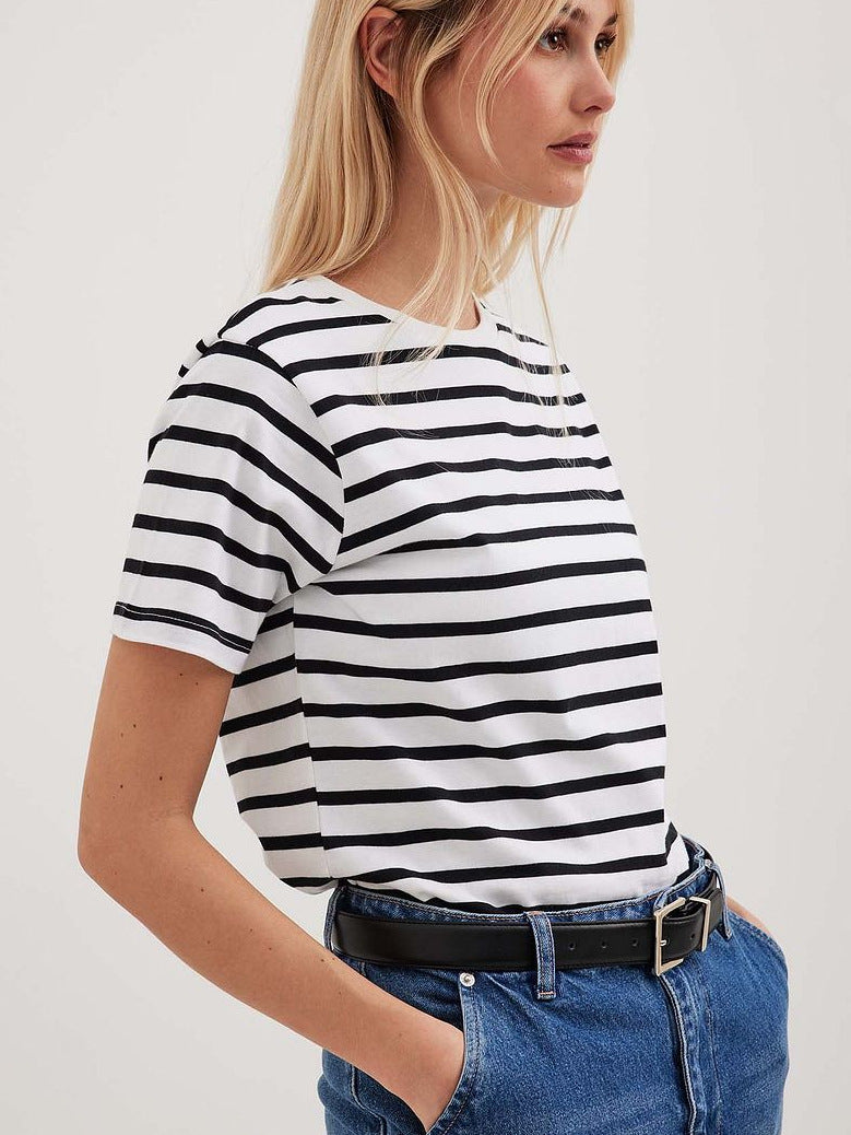 Blonde woman in black and white striped tee, paired with blue denim and black belt