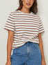 Woman in brown and white striped tee, blue denim skirt, warm smile