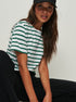 Woman in green and white striped tee, black cap, casual pose