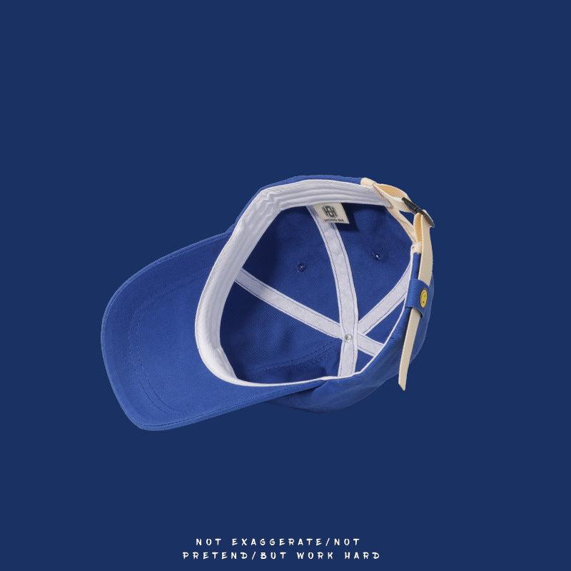 Interior view of blue baseball cap showing white lining and cream strap with smiley face detail