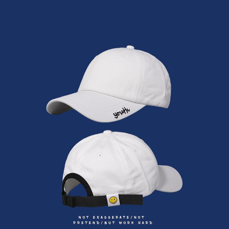White baseball cap with black "youth" embroidery and black adjustable strap with smiley face detail on navy background
