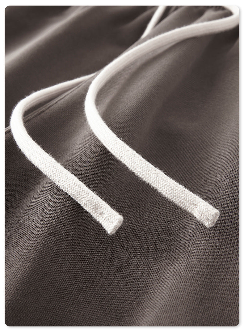 Close-up of gray sweatpants showing white drawstring and pocket detail against white background