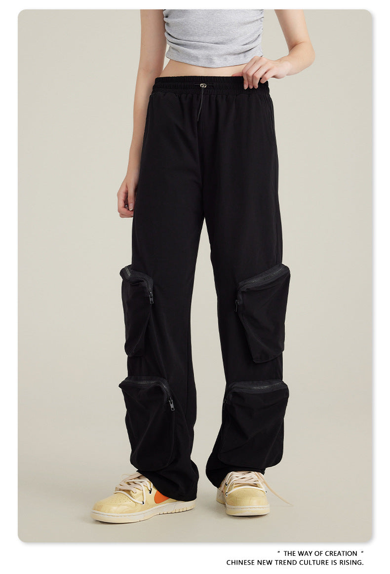 Side view of black cargo pants with elastic waistband and zippered cargo pockets paired with cream Nike sneakers