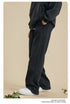 Side view of person wearing black sweatpants with side panel detail and white sneakers on beige background