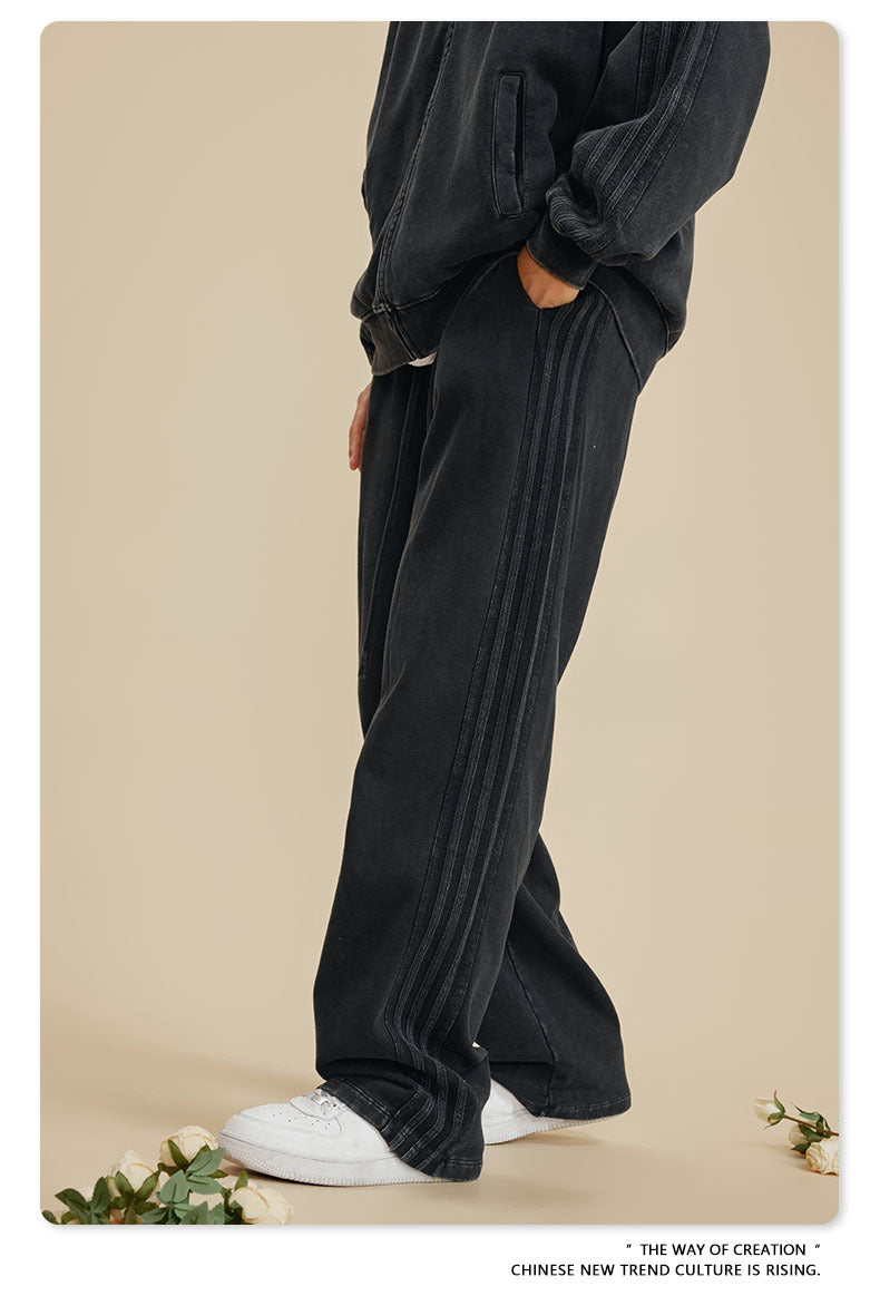Side view of person wearing black sweatpants with side panel detail and white sneakers on beige background