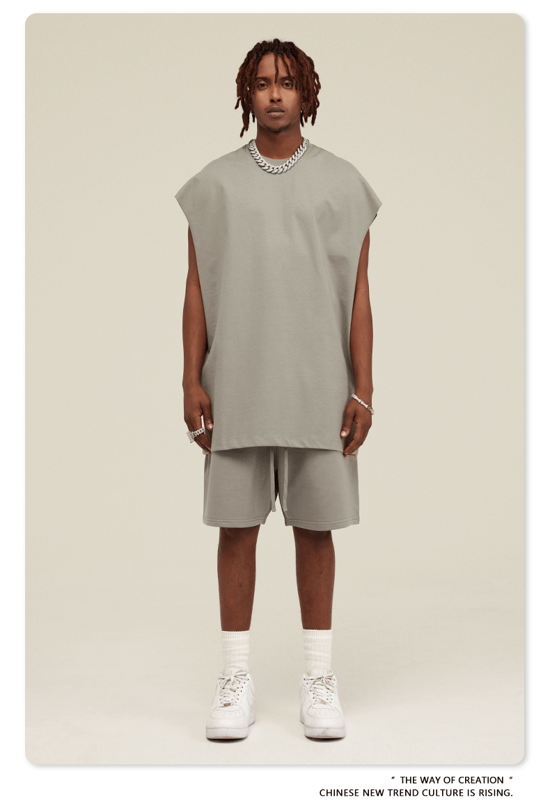 Male model wearing light gray oversized muscle tee and matching shorts with white Air Force 1 sneakers