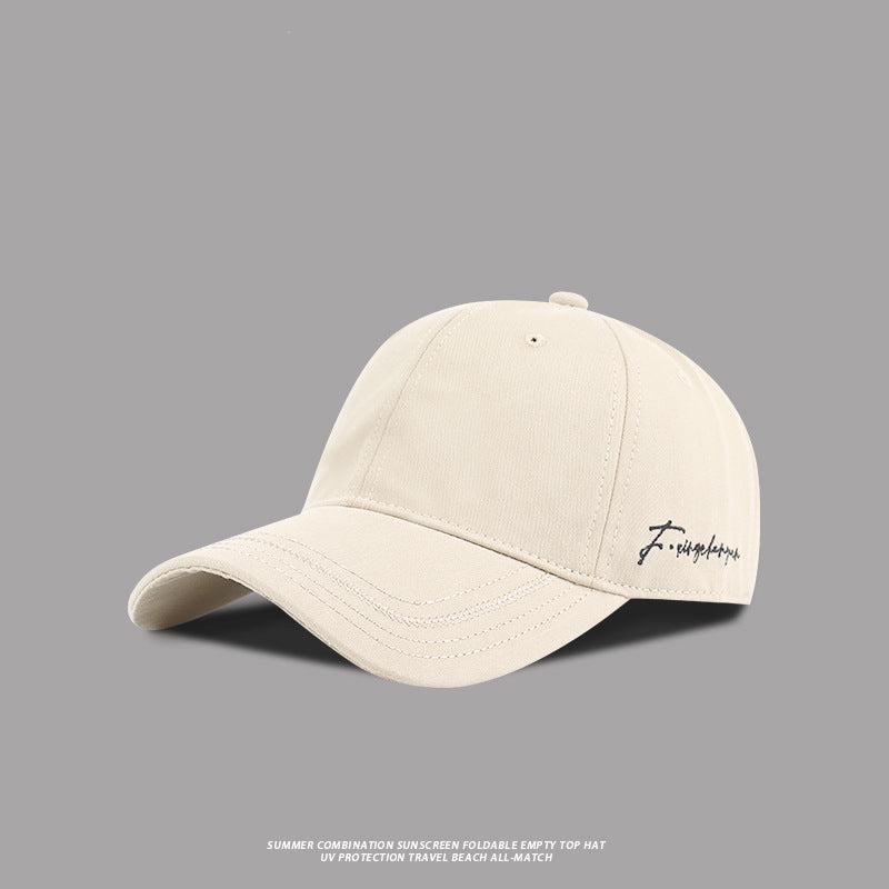 Beige baseball cap with black embroidered signature logo, minimalist casual style