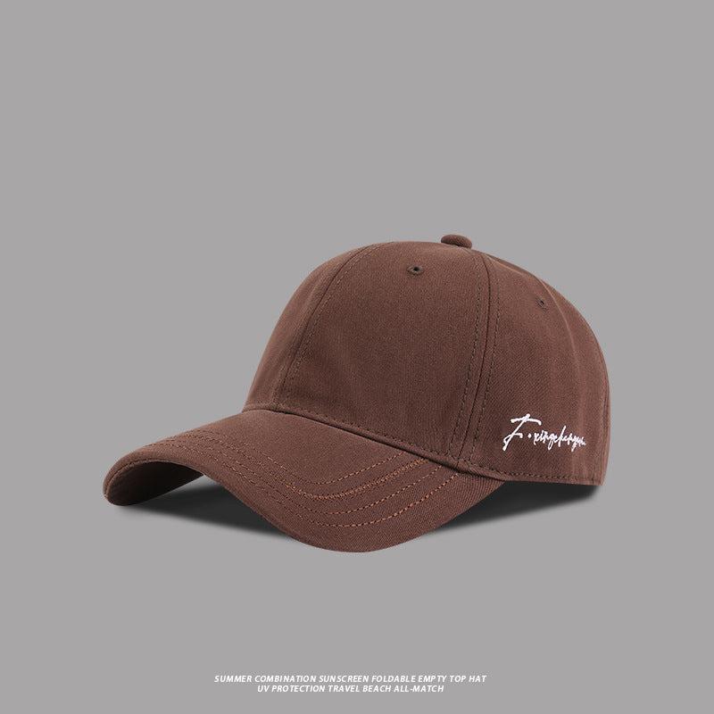 Brown baseball cap with white embroidered signature logo, classic streetwear design