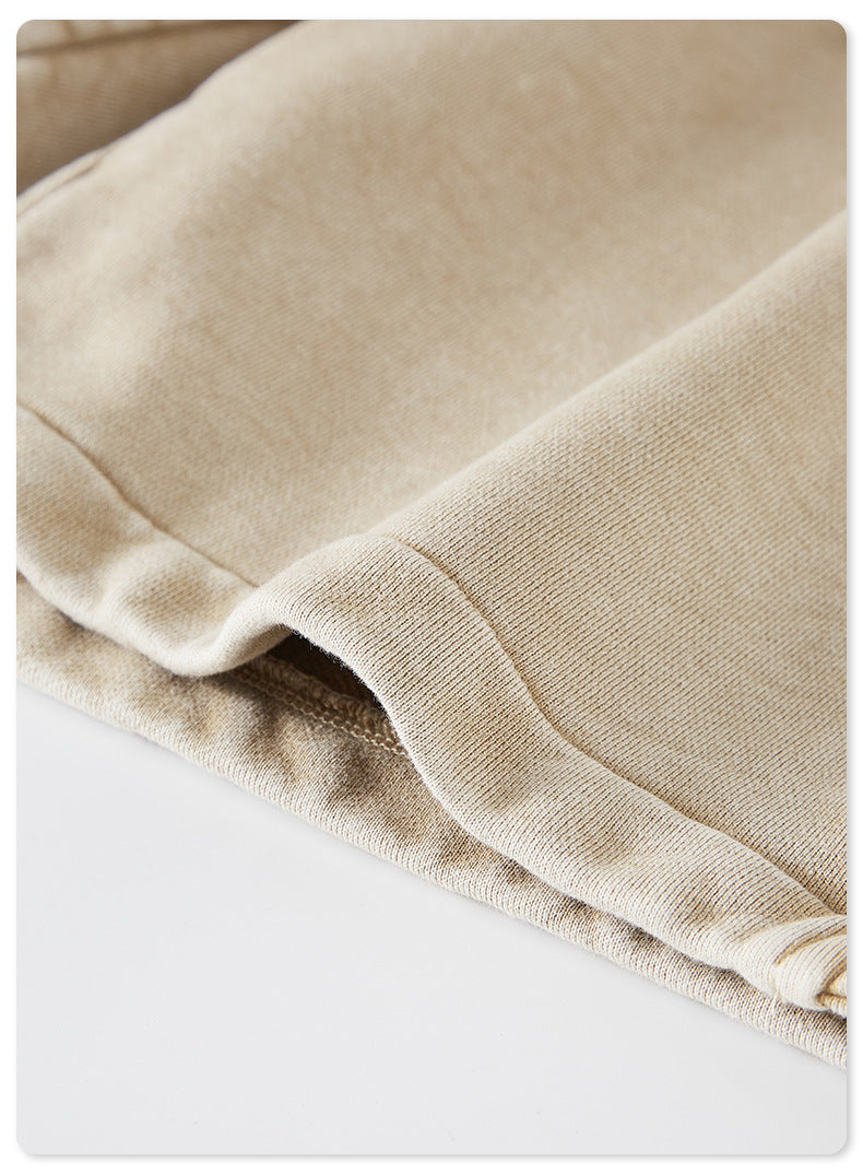 A close-up of the hem of beige washed shorts, featuring clean stitching and a slightly folded edge