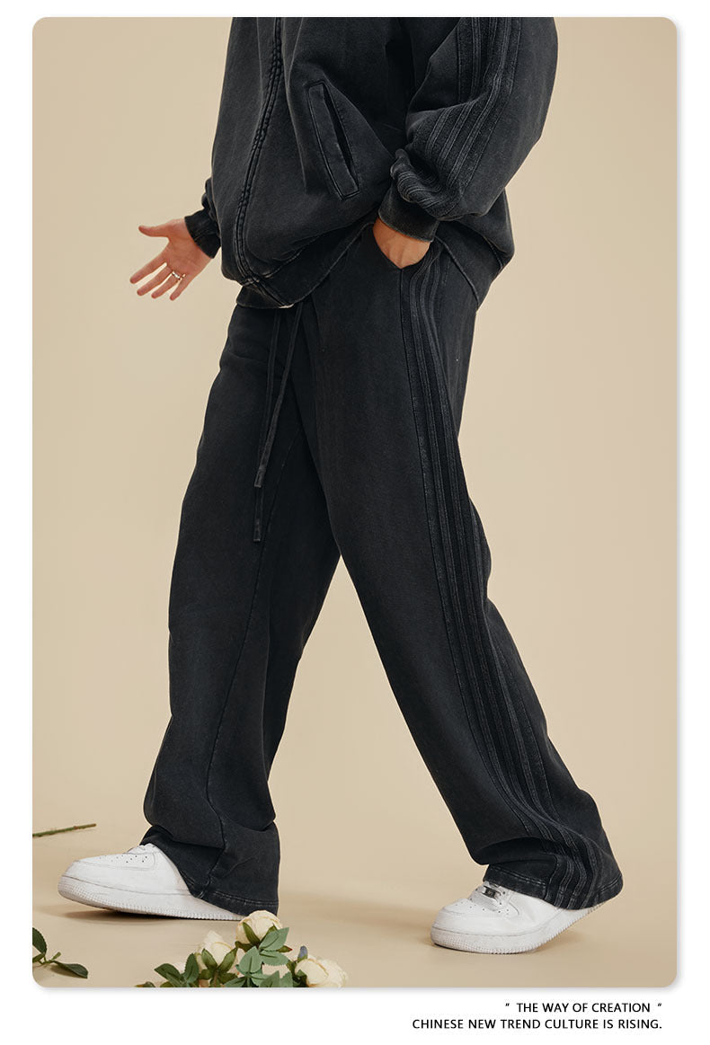 Person walking in black oversized sweatsuit with white sneakers on beige background with white flowers