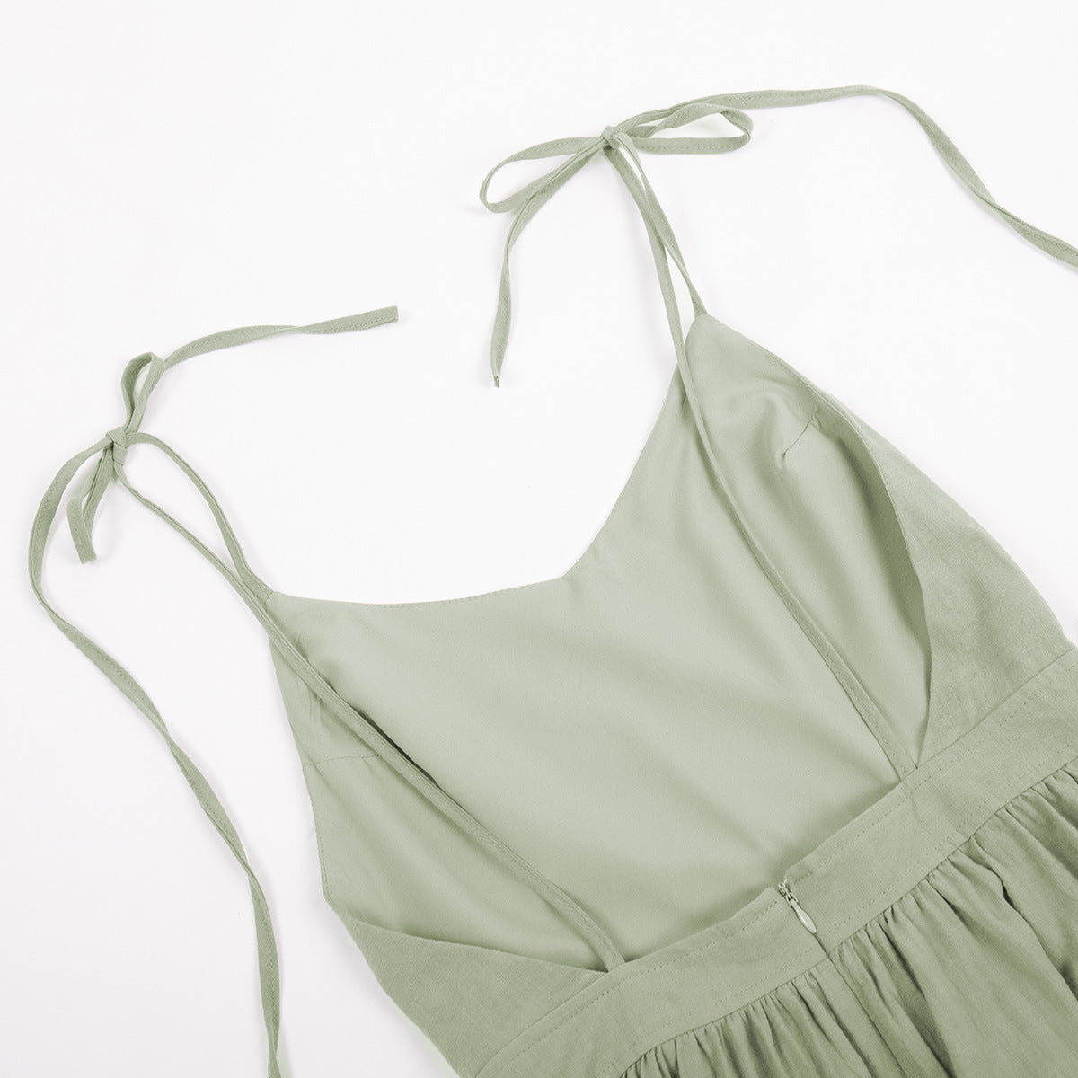 A sage green linen dress bodice with tie straps and V-neckline photographed flat against white background