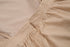 Close-up of beige linen dress showing zipper closure detail and gathered waistband against neutral background