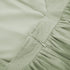 Close-up detail of sage green linen dress showing zipper closure and gathered waistband stitching