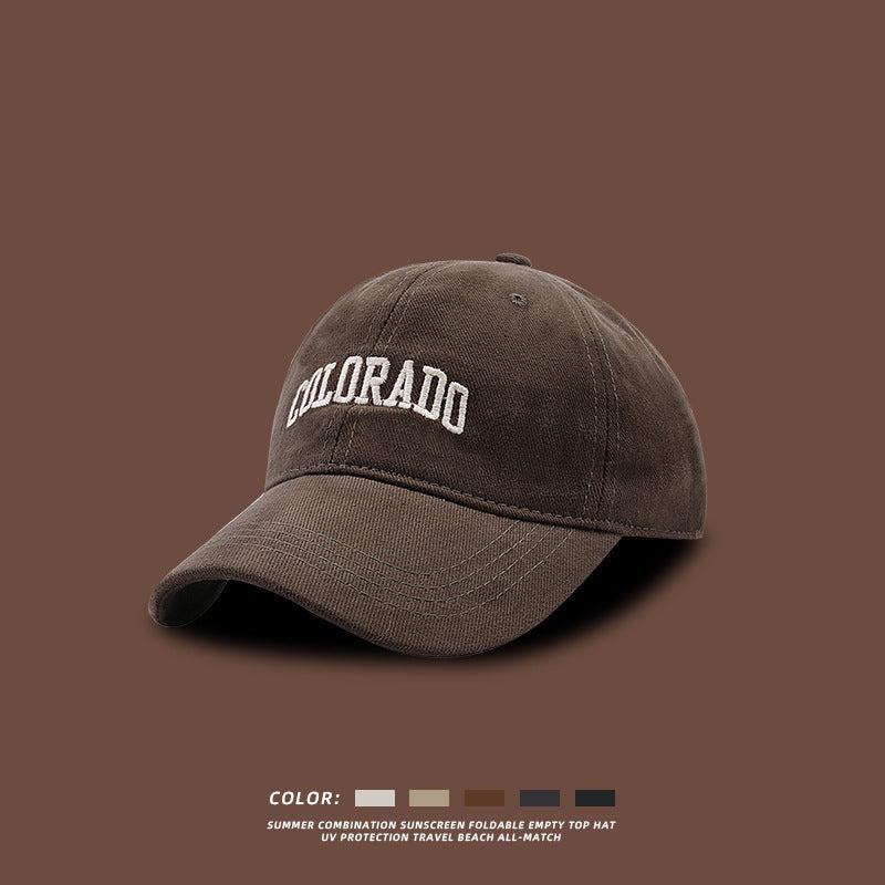 Dark gray baseball cap with white COLORADO embroidery shown against brown background with color options and summer protection features