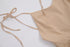 A beige linen tie-shoulder dress with string closures laid flat against white background, showing bodice detail