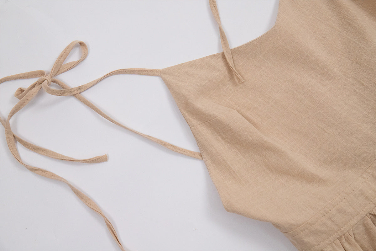 A beige linen tie-shoulder dress with string closures laid flat against white background, showing bodice detail