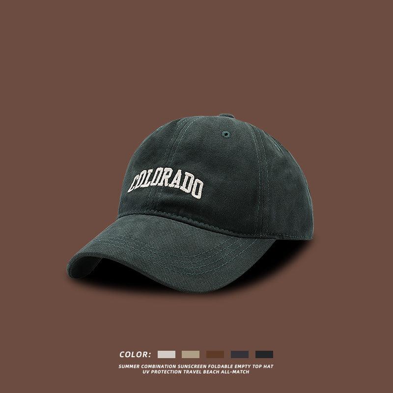 Forest green baseball cap with white COLORADO embroidery displayed against brown background with color selection options
