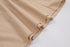 Close-up of beige linen fabric showing gathered hemline detail and stitching against white background