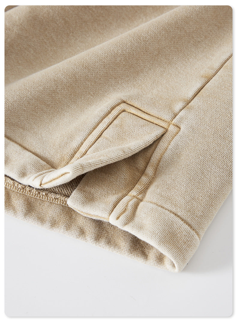 A detailed shot of a side vent on beige washed shorts, revealing reinforced stitching and a layered design