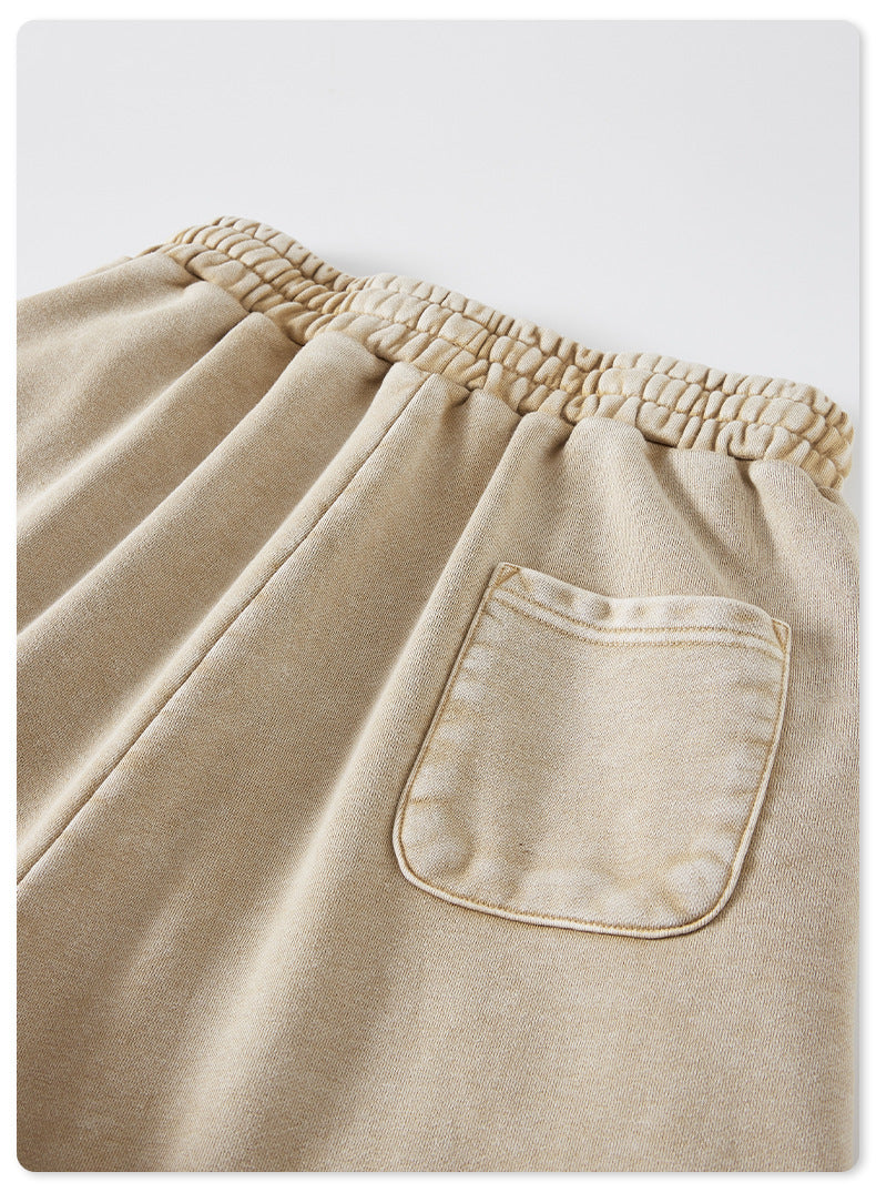 A close-up of the back pocket on beige washed shorts, featuring a simple rectangular design and visible stitching