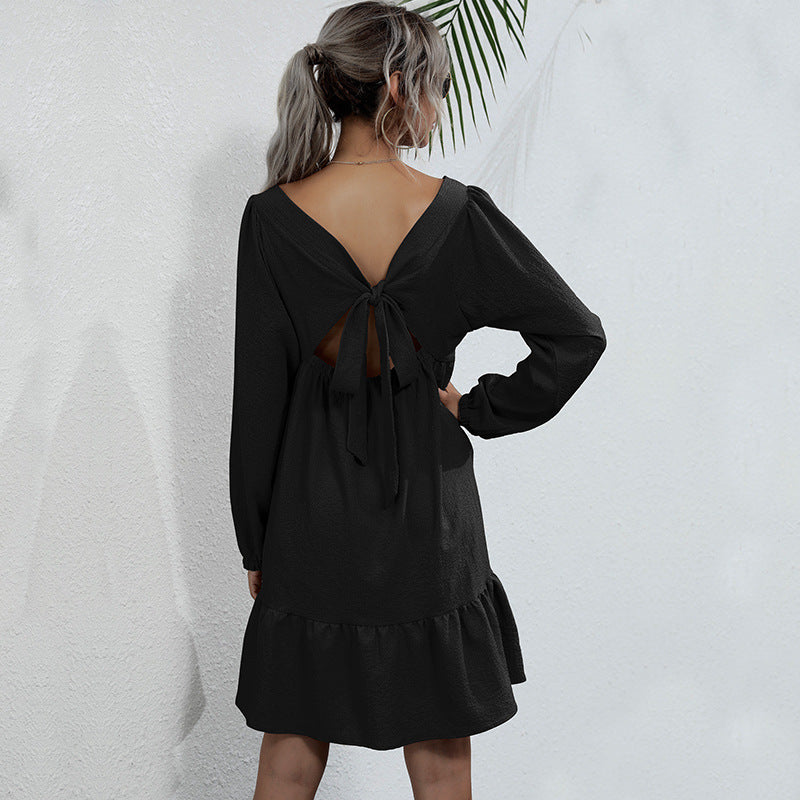 Back view of black babydoll dress revealing tie-back detail and tiered silhouette