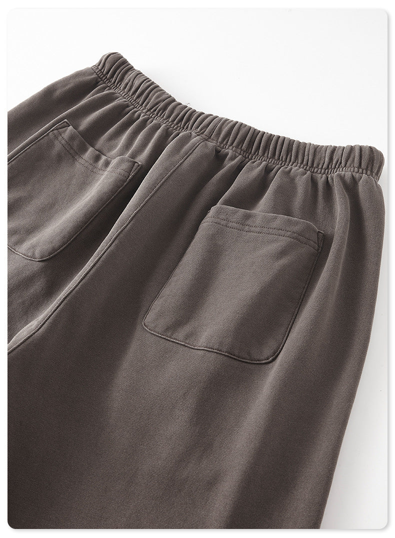 Close-up of charcoal gray sweatpants showing elastic waistband and back pockets on white background.