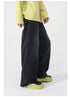 A side view of faded black wide-leg jeans, styled with a yellow sweater and green platform boots, showcasing the relaxed fit
