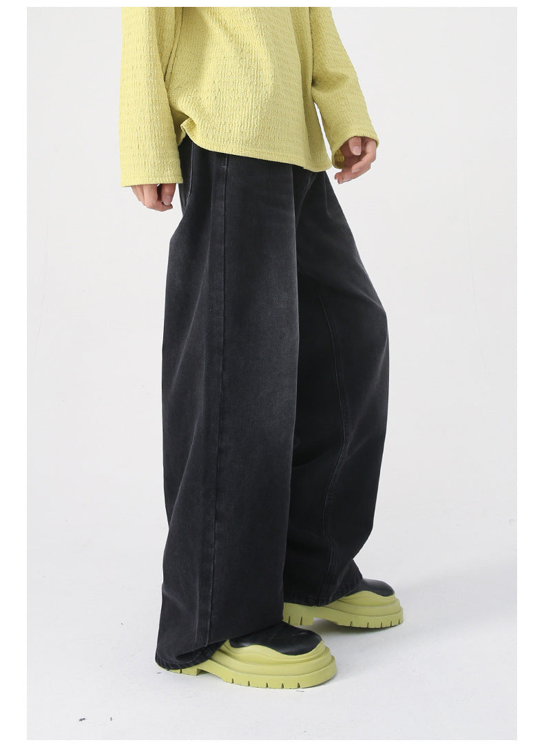 A side view of faded black wide-leg jeans, styled with a yellow sweater and green platform boots, showcasing the relaxed fit