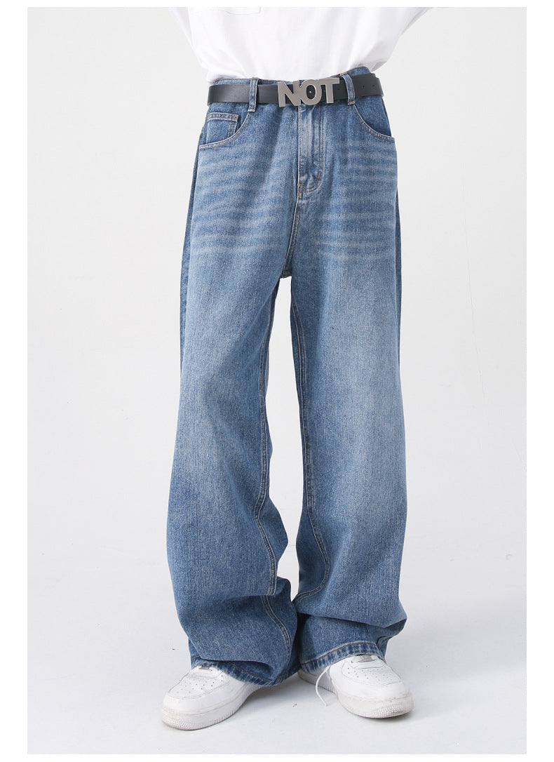 A front view of blue wide-leg jeans worn with a black "NOT" belt, a white shirt, and white sneakers, showcasing the relaxed fit