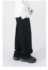 A side view of black wide-leg jeans with a high waist and relaxed fit, paired with a white long-sleeve shirt and black sneakers
