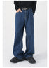 A model wears dark blue wide-leg jeans with a "NOT" belt, a black long-sleeve shirt, and black sneakers, posing with hands in pockets