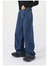A side view of dark blue wide-leg jeans, showing their oversized fit, worn with a black shirt, "NOT" belt, and black sneakers