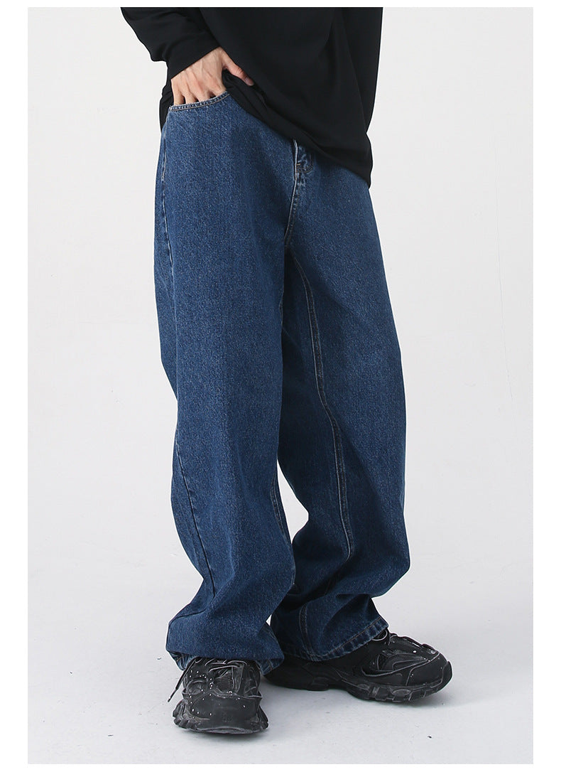 A close-up of dark blue wide-leg jeans, highlighting the high waist and loose silhouette, styled with a black top and sneakers