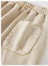 A macro view of the back pocket on beige shorts, showing a slight puffiness in the fabric and reinforced stitching