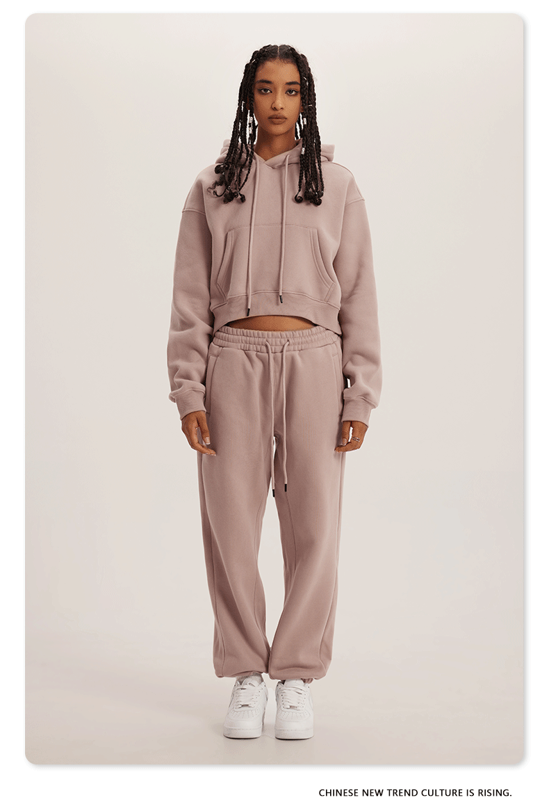 Dusty Pink Sweatshirt and Joggers Set – Model in a soft pink cropped hoodie and sweatpants, paired with white sneakers