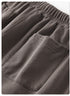 Detail shot of charcoal gray sweatpants fabric with elastic waistband and patch pocket visible on white background