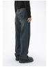 A model is turned slightly, showing the back of dark-wash wide-leg jeans with two back pockets, standing against a white backdrop