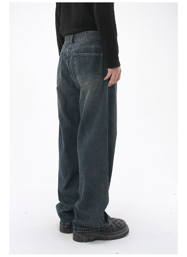 A model is turned slightly, showing the back of dark-wash wide-leg jeans with two back pockets, standing against a white backdrop