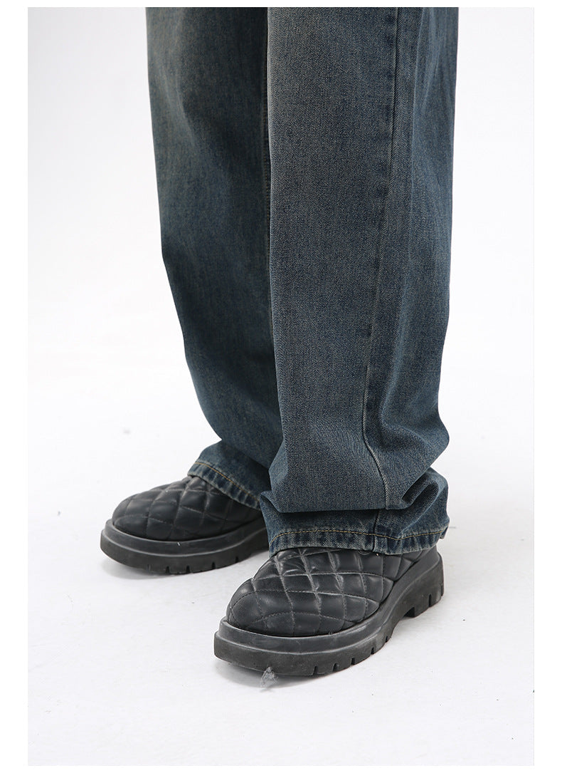 A close-up of the hem of dark-wash wide-leg jeans, slightly pooling over black quilted platform shoes